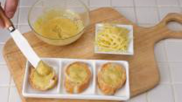Extiende la mantequilla preparada sobre las tostadas y ralla abundante queso por encima