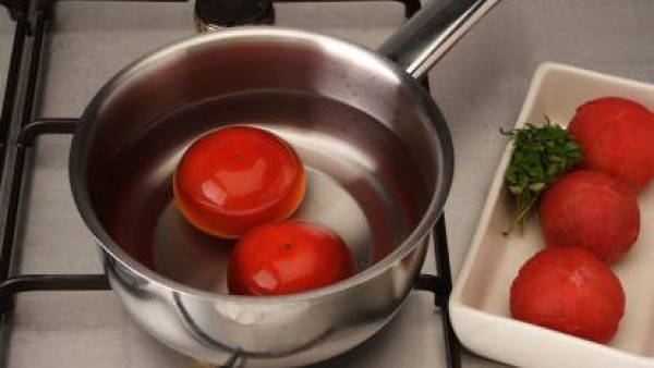 Precalienta el horno a 180ºC. Haz un corte en forma de cruz en la base de los tomates y escaldarlos durante unos segundos. Escúrrelos y deja que se templen.  Pélalos con cuidado de que no se deshagan 