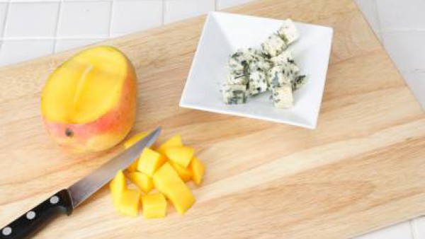 Pelar el mango, separar la pulpa del hueso y cortarla en dados. Cortar el queso azul en daditos.