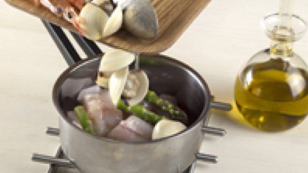 Tapa la sartén y deja cocer unos 2 minutos. Gira el pescado y coloca las gambas para que se sumerjan en la salsa. Deja cocer 5 minutos más e incorpora las almejas.