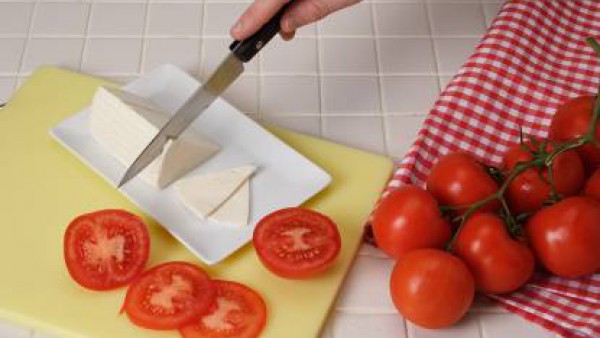 Lava los tomates y córtalos a rodajas. Colócalos en el fondo del plato. Pon las sardinas y el queso a trocitos por encima. Aliña el plato con el aceite de albahaca y la tapenade.