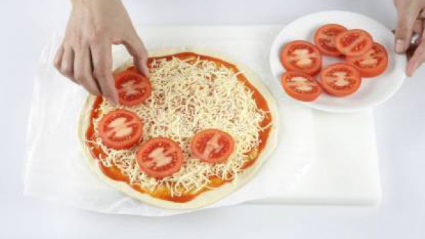 A continuación añade los tomates cortados en rodajas de forma uniforme por encima del queso.