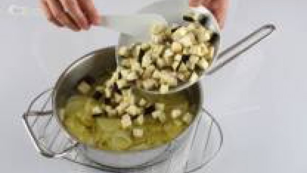 Pela y corta la cebolla en tiras finas y la patata en rodajas. En una cazuela con una cucharada de aceite de oliva, pon a pochar la cebolla junto con la patata. Pela y corta la berenjena a daditos peq