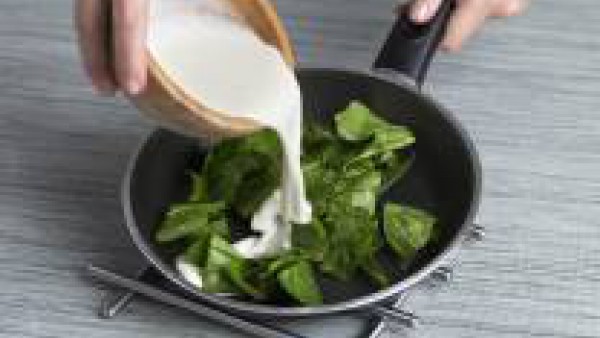 Saltea unas hojas de espinaca fresca con un chorrito de aceite de oliva. Sirve la crema en platos, añade las espinacas salteadas por encima y unas gotas de nata para decorar.