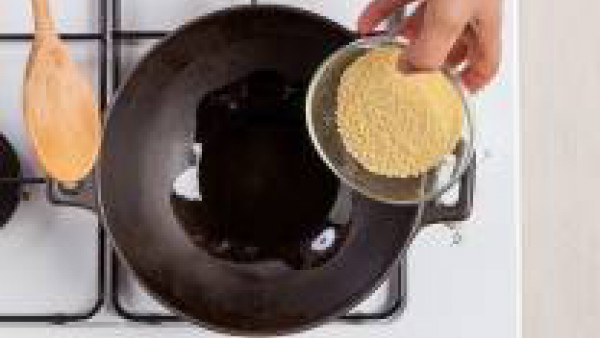 Tuesta el cuscús durante unos minutos en un wok untado con aceite de oliva virgen extra. Sazona con sal y pimienta.   Mientras tanto, hidrata las pasas en agua caliente. 