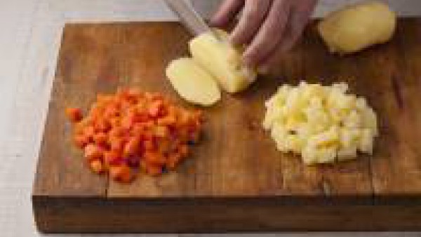 Pela las patatas y córtalas en daditos pequeños. Corta del mismo modo las zanahorias.  En un cazo cocina los huevos 12 minutos, escúrrelos, enfríalos y pélalos. Corta los huevos en daditos.