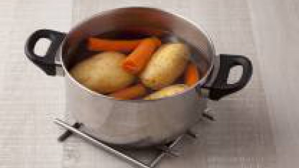 Cuece las patatas enteras en una olla con agua abundante durante 25-30 minutos. A mitad de cocción añade las zanahorias peladas. Deja cocinar hasta que las verduras estén tiernas, luego escúrrelas y e