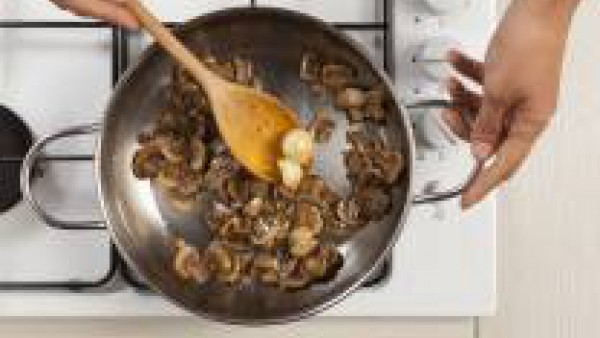 Limpia los champiñones y córtalos en rodajas finas. En una sartén, fríelos con los 2 dientes de ajo y 1 cucharada de aceite de oliva. Precalienta el horno a 200°C.