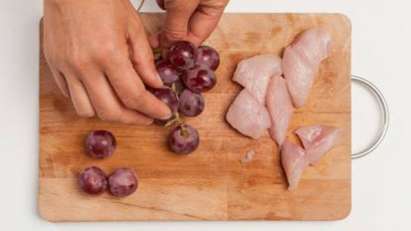 Lava las uvas y separa las bayas de los tallos; corta la pechuga de pollo en cuadrados. Prepara las brochetas alternando las uvas con los trozos de pollo.